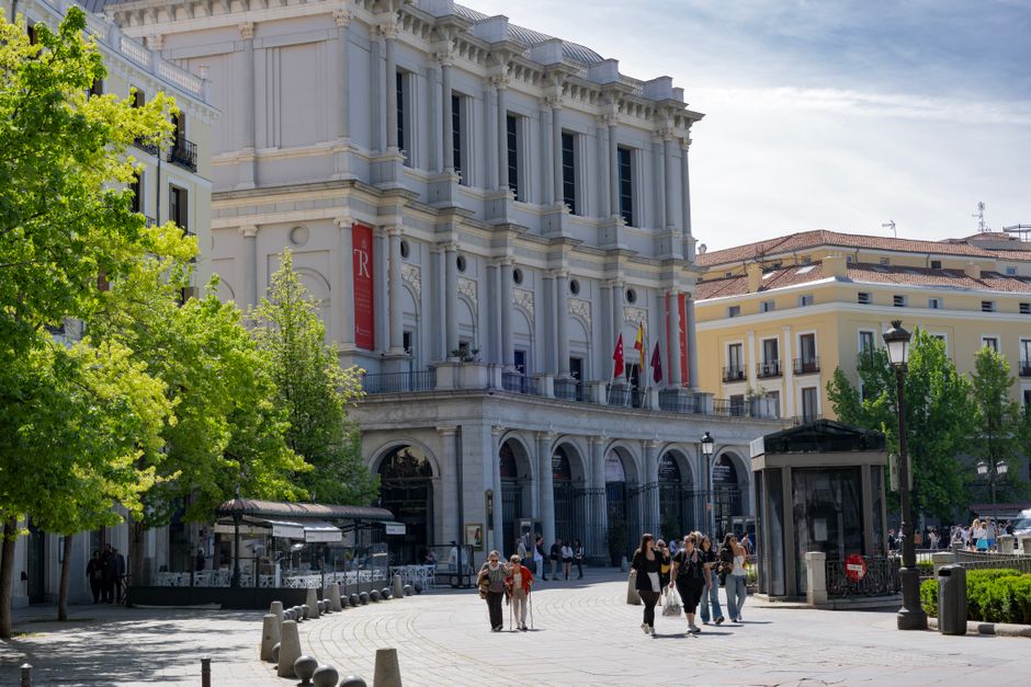 Calle de Madrid con gente disfrutando de un evento cultural y el Palacio Real al fondo.