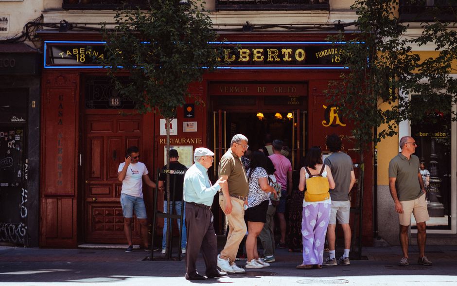Personas en un barrio alternativo de Madrid, rodeados de arte urbano y cultura local.